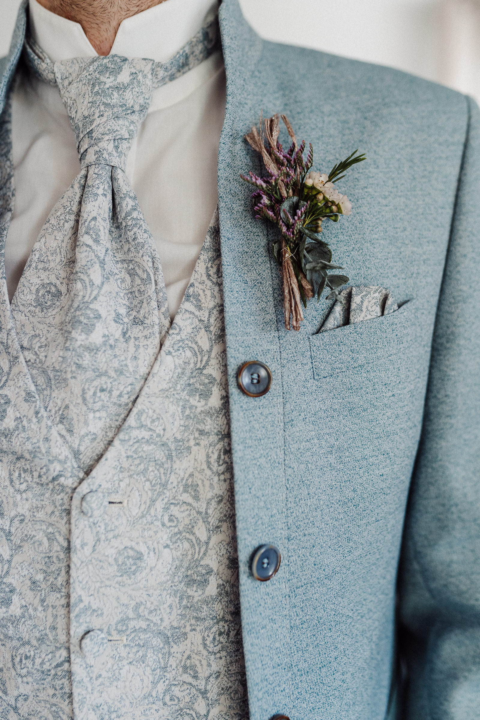 Blauer Anzug eines Bräutigams mit Sträußchen und Einstecktuch.
