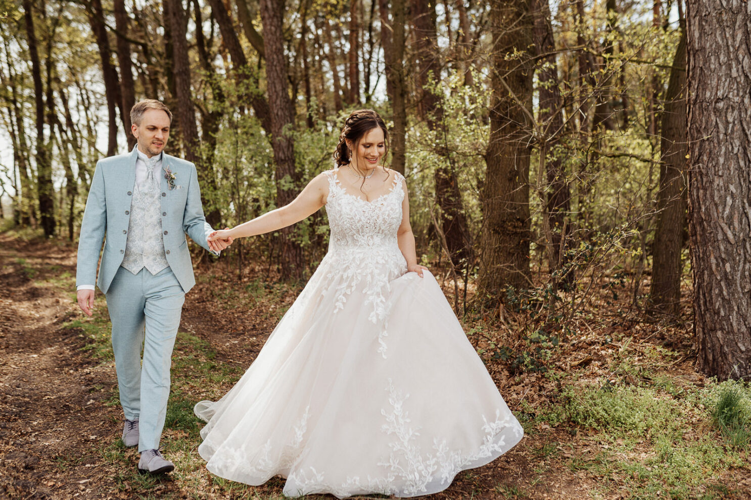 Hochzeitsfotos Brautpaar geht durch den Wald in Rietberg Hand in Hand