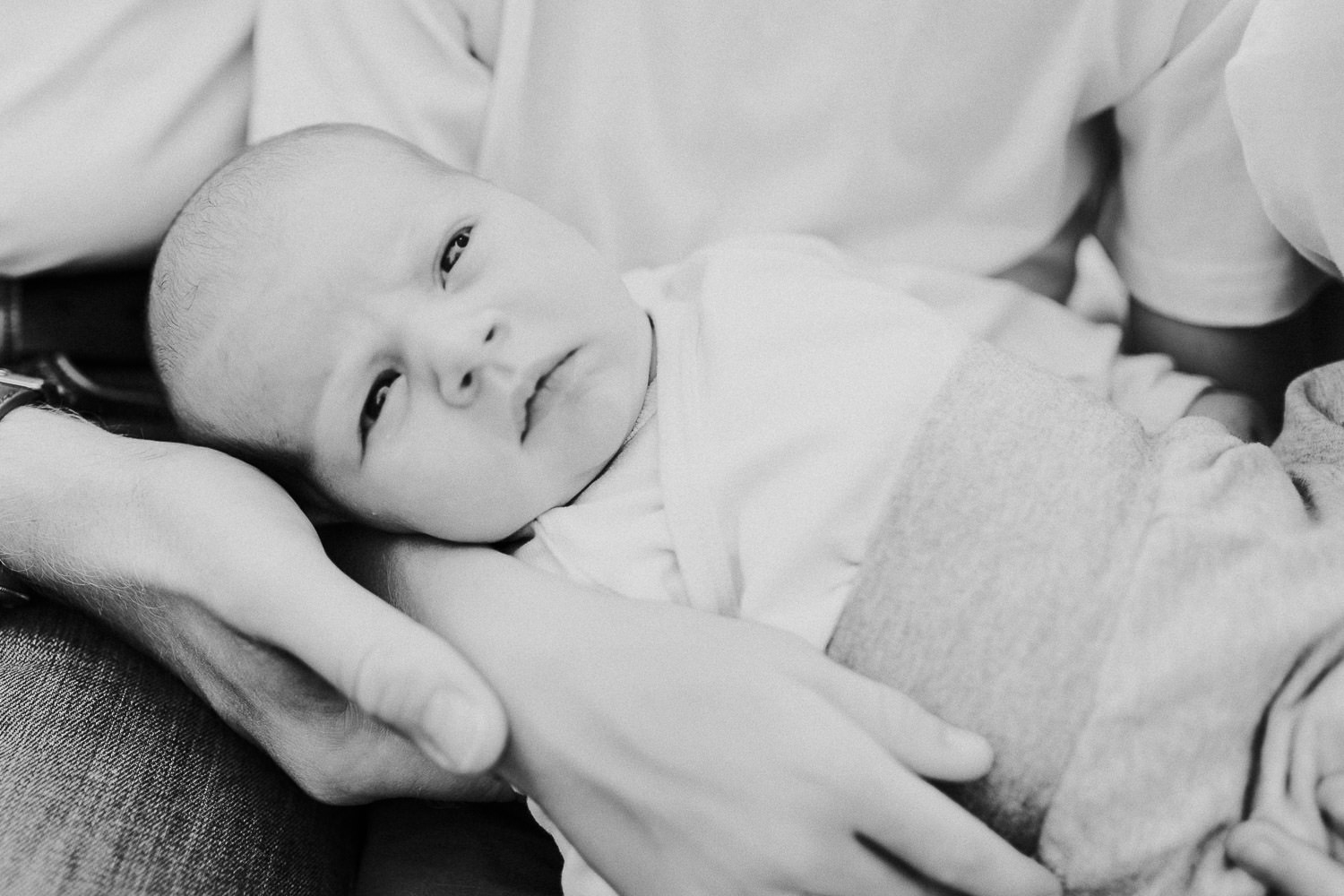 Baby liegt auf den Knien der Eltern
