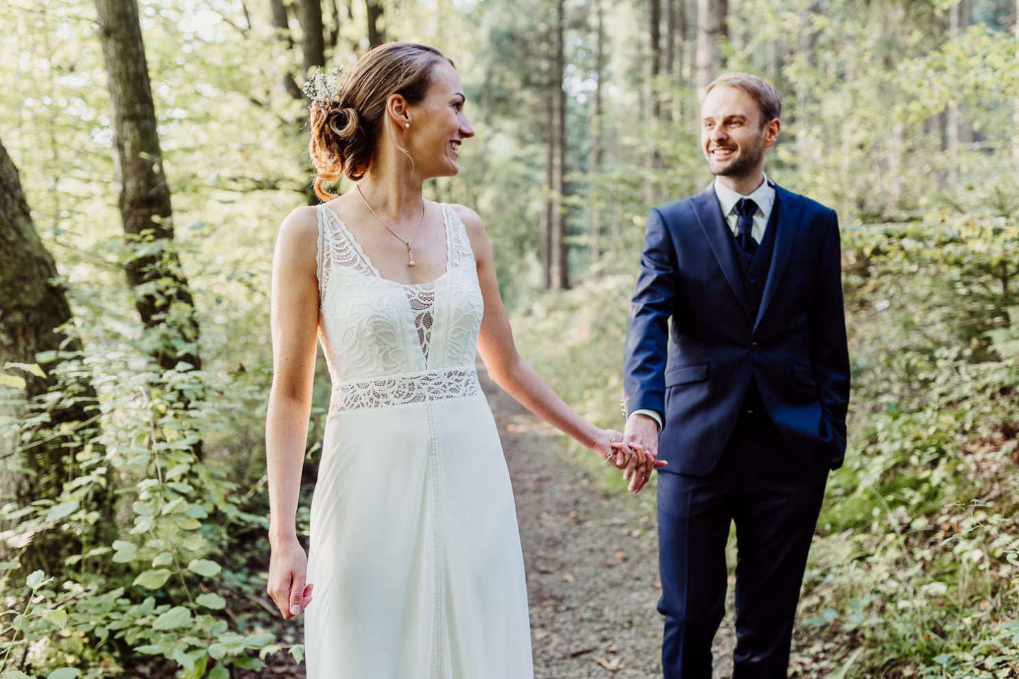 Hochzeitsfotograf Bielefeld Brautpaar geht Hand in Hand durch den Wald